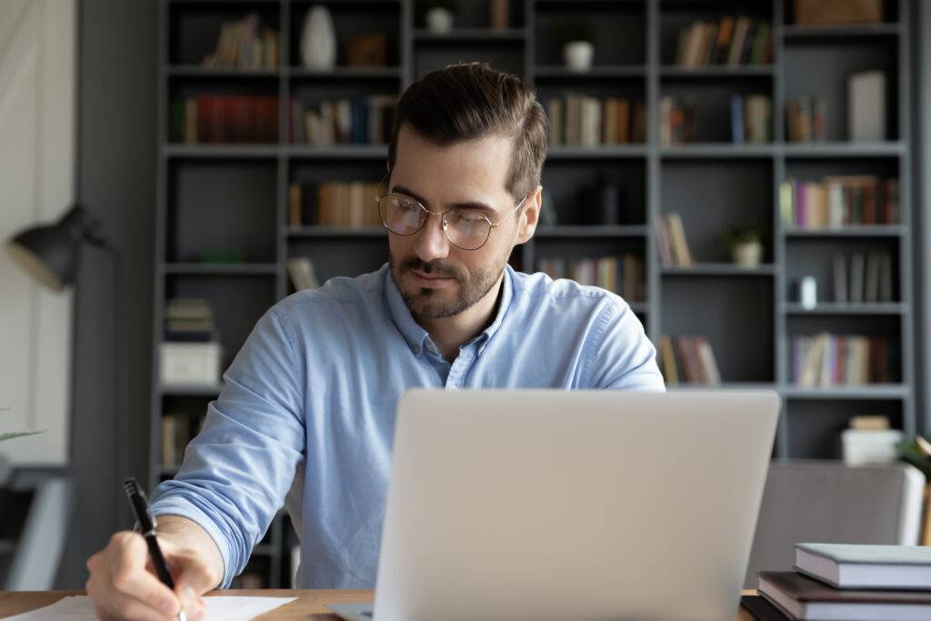 A man studies for an exam sitting behind a laptop.