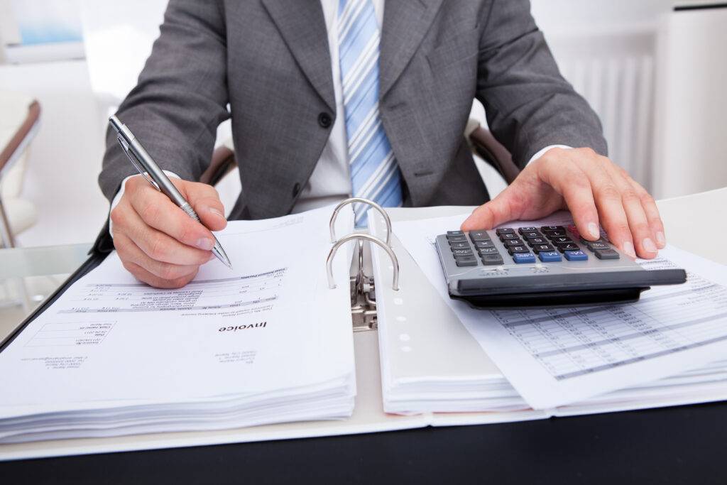A businessman uses a calcuator and takes notes.