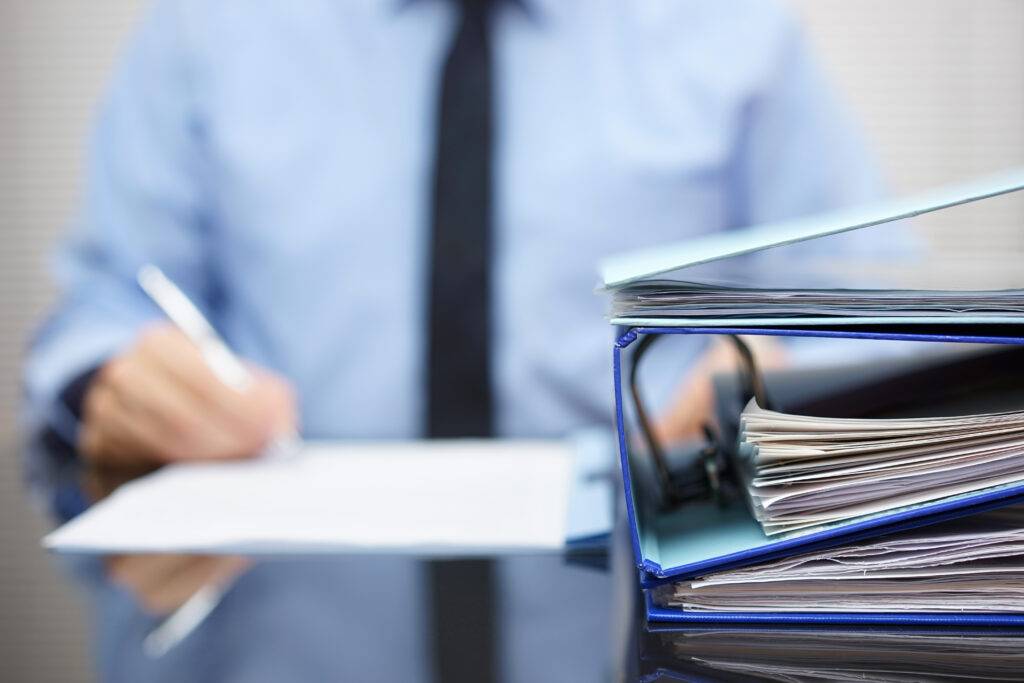 A businessman works behind a stack of binders.