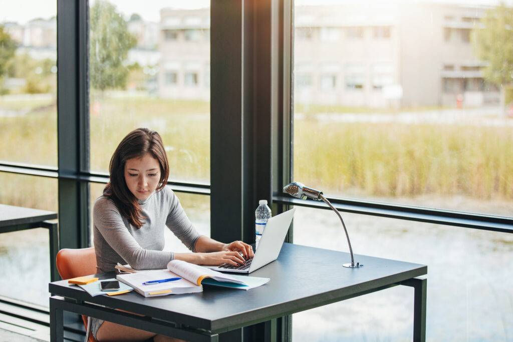 A young professional woman works on a laptop.